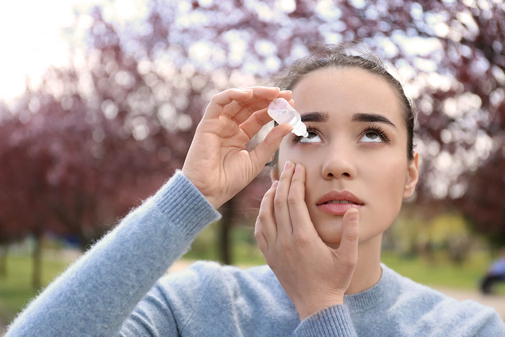 Young woman using eye drops